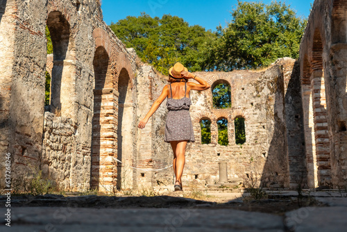 Fotografi Woman tourist walking in Great basilica in the archaeological ruins of Butrint o