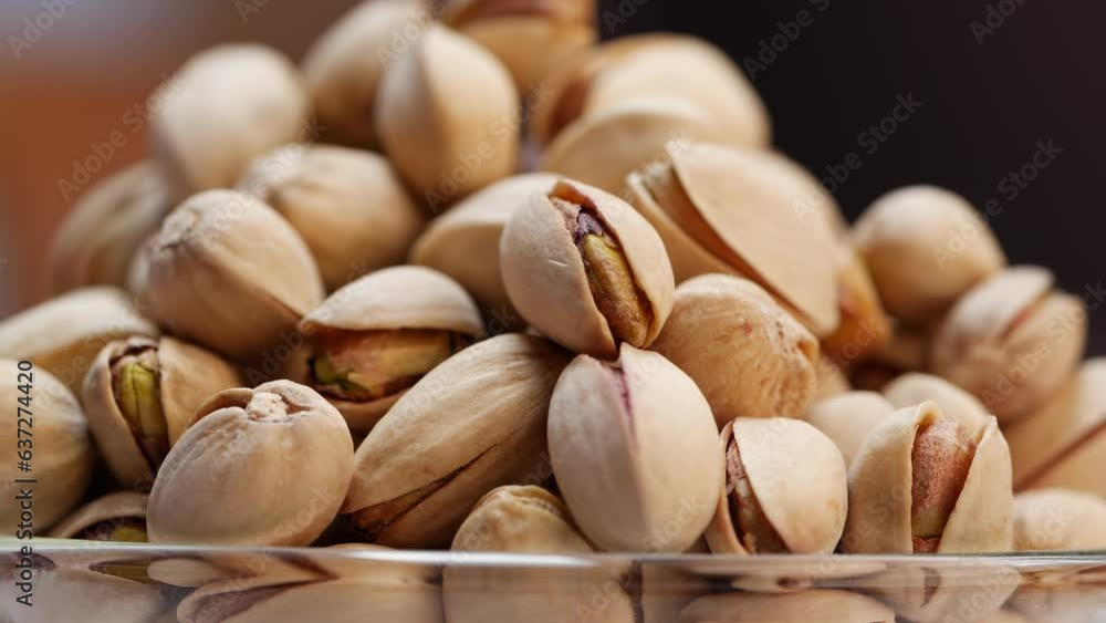 A pile and bowl of pistachios on a table A pile and bowl of pistachios on a table