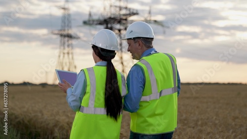 Happy electricians with tablet walk to power transmission lines at sunset © SUPER FOX