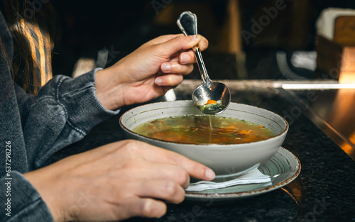 A woman in a cafe eats a low-calorie vegetable soup.