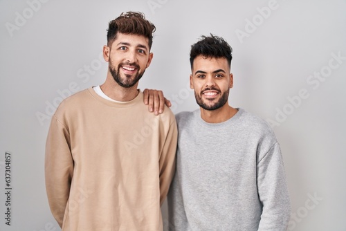 Young homosexual couple standing over white background with a happy and cool smile on face. lucky person.