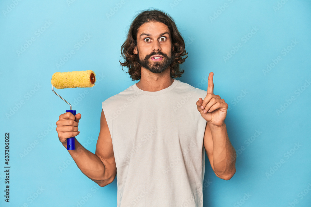 Bearded man painting with a yellow roller having some great idea, concept of creativity. Bearded man painting with a yellow roller having some great idea, concept of creativity.