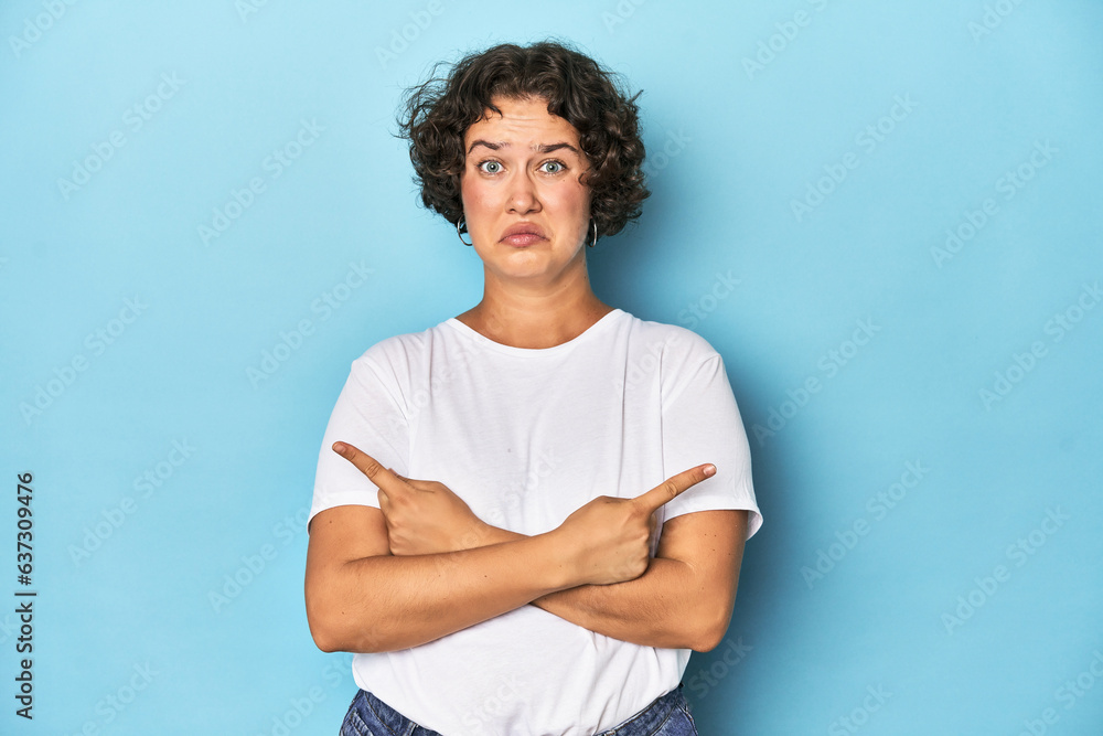 Young Caucasian woman with short hair points sideways, is trying to choose between two options. Young Caucasian woman with short hair points sideways, is trying to choose between two options.