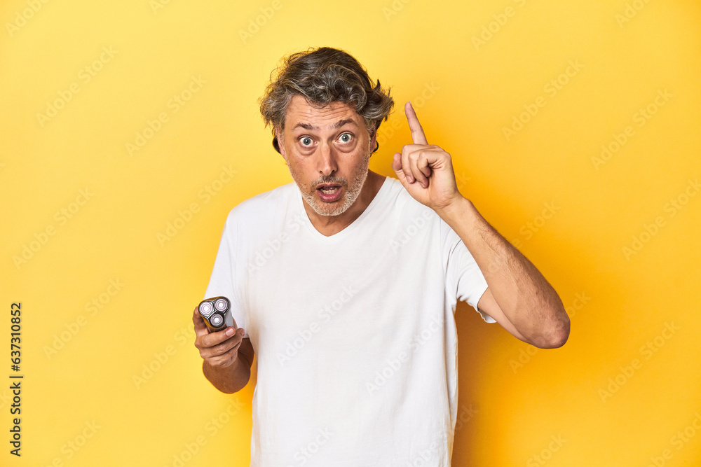 Man holding a razor, yellow studio background having an idea, inspiration concept. Man holding a razor, yellow studio background having an idea, inspiration concept.