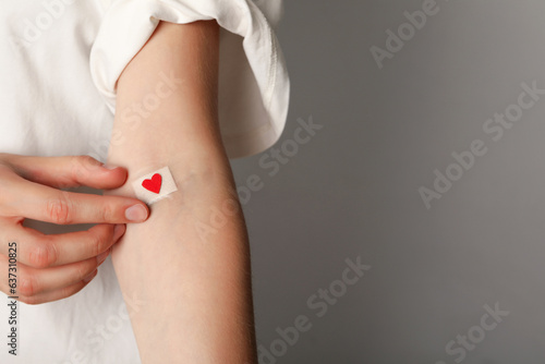 Blood donation. Blood donor with bandage and red heart after donating blood, place for text