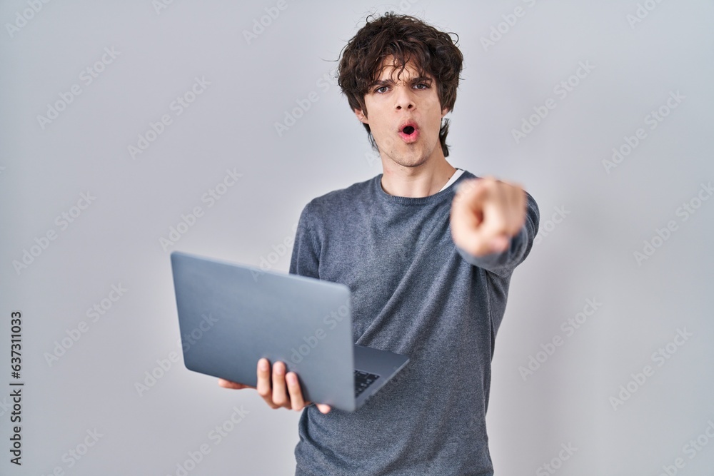 Young man working using computer laptop pointing with finger to the camera and to you, confident gesture looking serious Young man working using computer laptop pointing with finger to the camera and to you, confident gesture looking serious