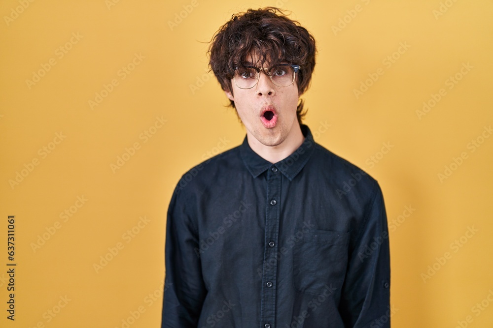 Obraz premium Young man wearing glasses over yellow background afraid and shocked with surprise expression, fear and excited face.
