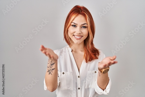 Young caucasian woman standing over isolated background smiling cheerful offering hands giving assistance and acceptance.