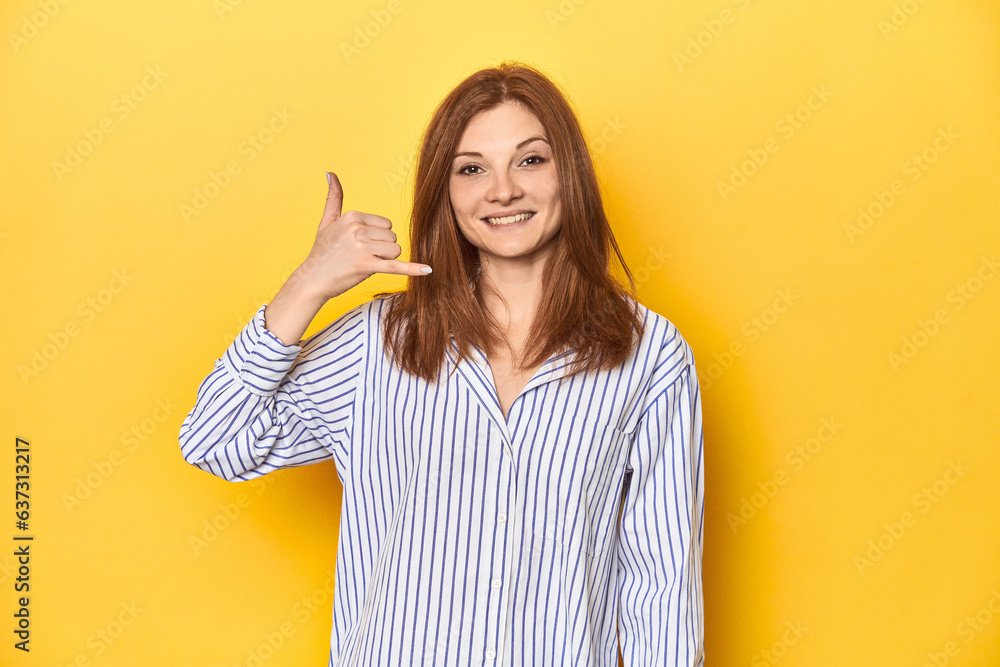 Business-dressed redhead, formal studio shot showing a mobile phone call gesture with fingers. Business-dressed redhead, formal studio shot showing a mobile phone call gesture with fingers.