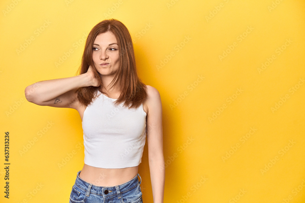 Redhead in white tank top, relaxed studio pose touching back of head, thinking and making a choice. Redhead in white tank top, relaxed studio pose touching back of head, thinking and making a choice.