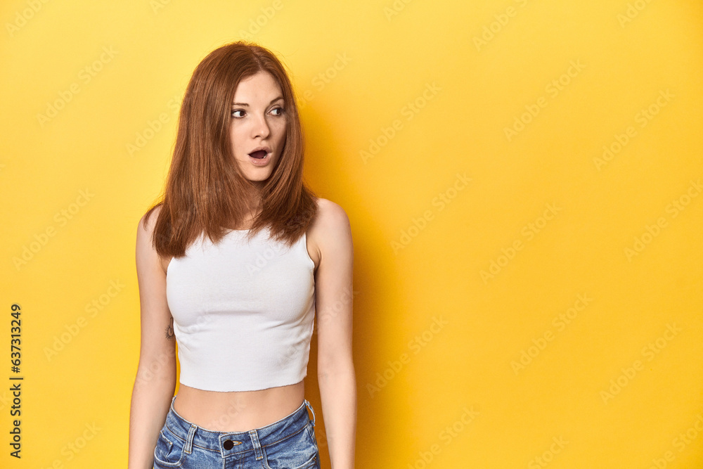 Redhead in white tank top, relaxed studio pose being shocked because of something she has seen. Redhead in white tank top, relaxed studio pose being shocked because of something she has seen.