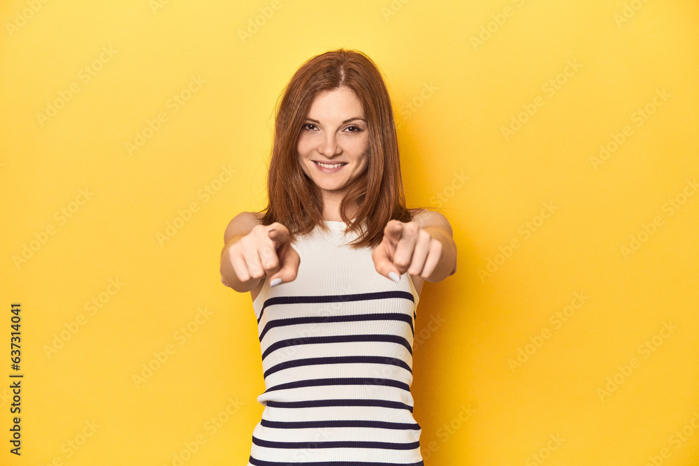 Redhead in a tank top, casual studio shot cheerful smiles pointing to front. Redhead in a tank top, casual studio shot cheerful smiles pointing to front.