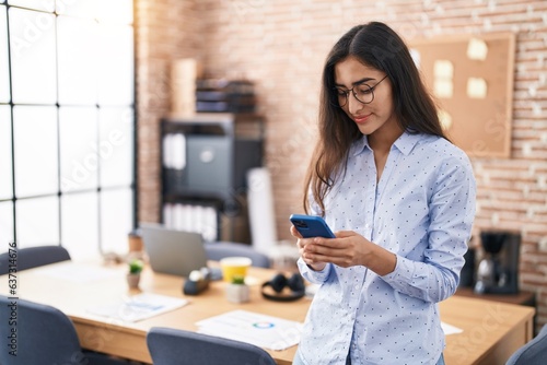 Young hispanic girl business worker smiling confident using smartphone at office