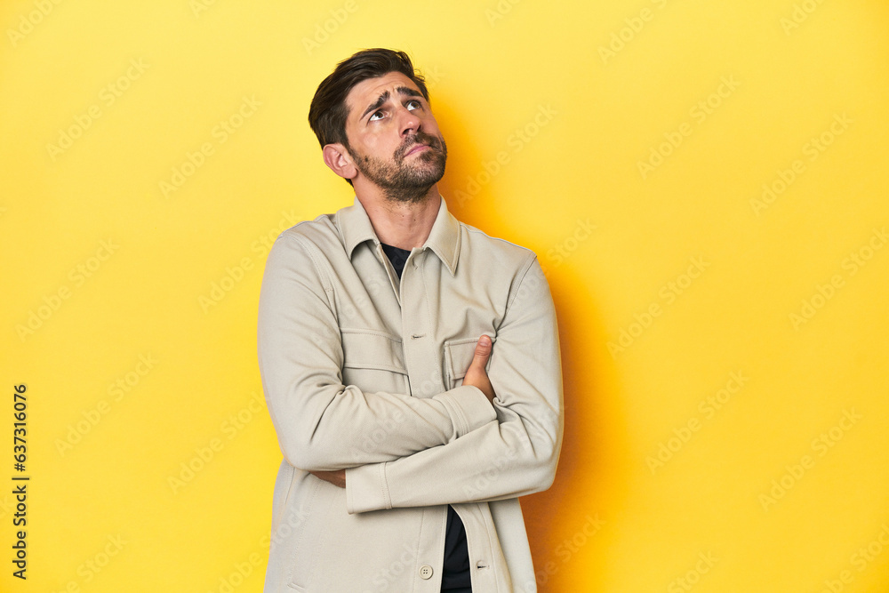 Caucasian man in grey shirt, studio shot on yellow dreaming of achieving goals and purposes Caucasian man in grey shirt, studio shot on yellow dreaming of achieving goals and purposes