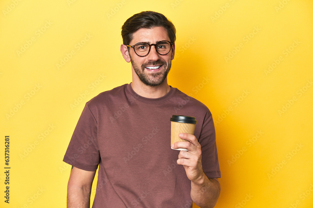 Man holding a takeaway coffee on a yellow studio background. Man holding a takeaway coffee on a yellow studio background.