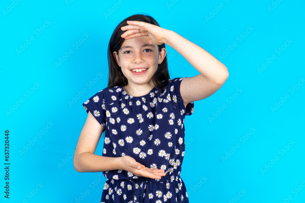Caucasian kid girl wearing floral dress over blue background gesturing with hands showing big and large size sign, measure symbol. Smiling looking at the camera. Caucasian kid girl wearing floral dress over blue background gesturing with hands showing big and large size sign, measure symbol. Smiling looking at the camera.