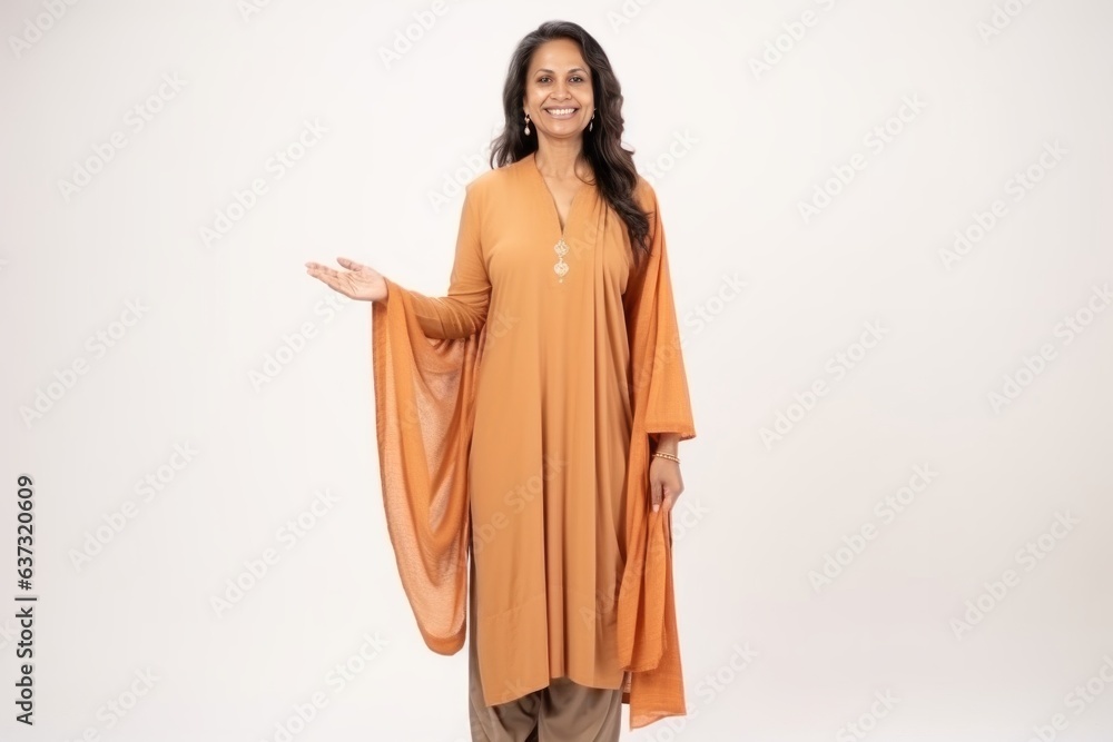 Medium shot portrait of an Indian woman in her 50s wearing thobe or dishdasha against a white background Medium shot portrait of an Indian woman in her 50s wearing thobe or dishdasha against a white background