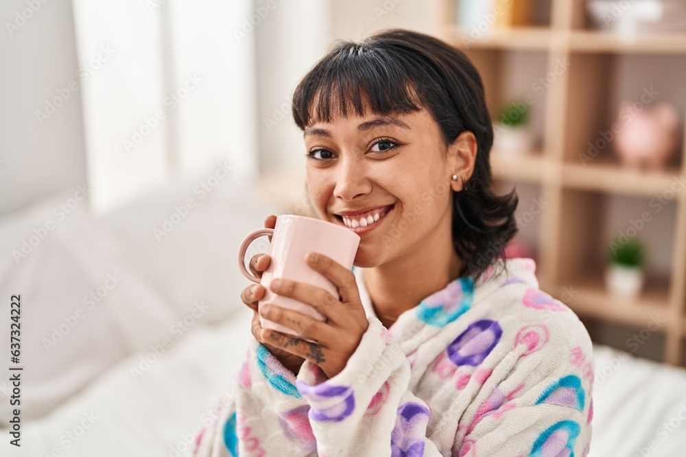 Young beautiful hispanic woman drinking cup of coffee sitting on bed at bedroom Young beautiful hispanic woman drinking cup of coffee sitting on bed at bedroom