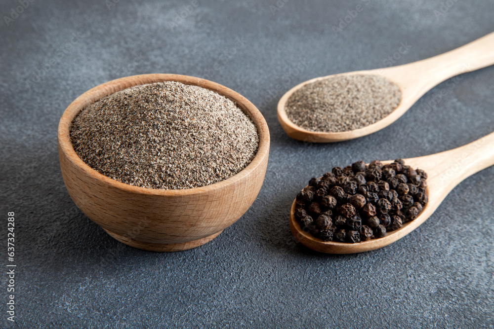 Ground black pepper with grains of black pepper on dark background Ground black pepper with grains of black pepper on dark background