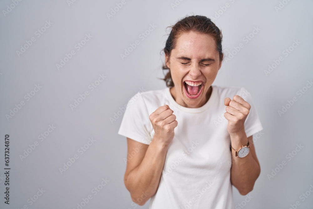 Beautiful brunette woman standing over isolated background excited for success with arms raised and eyes closed celebrating victory smiling. winner concept. Beautiful brunette woman standing over isolated background excited for success with arms raised and eyes closed celebrating victory smiling. winner concept.