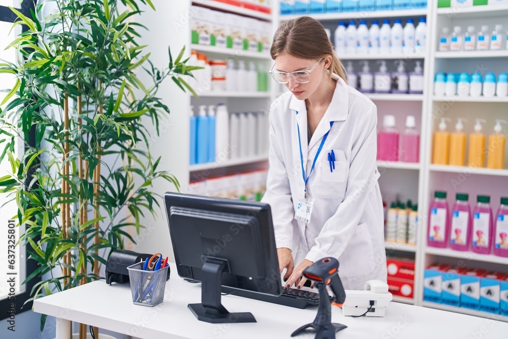 Young blonde woman pharmacist smiling confident using computer at pharmacy