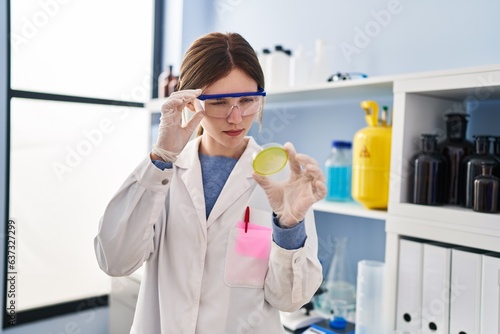 Young blonde woman scientist looking sample with serious expression at laboratory