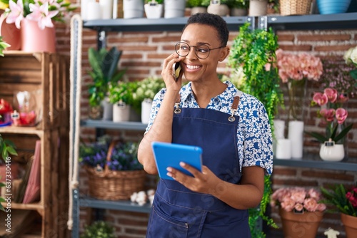African american woman florist talking on smartphone using touchpad at florist