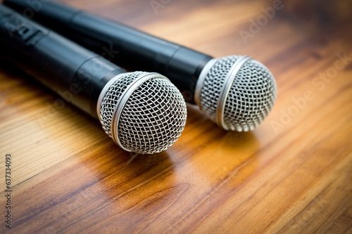 Two radio microphones lying on a wooden table surface.