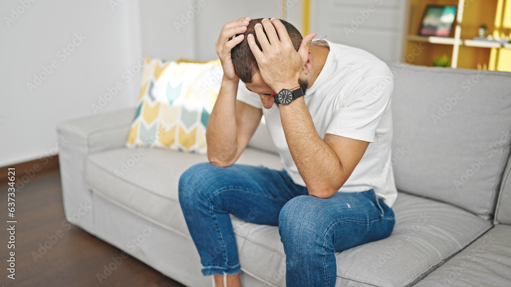 Young hispanic man stressed sitting on sofa at home Young hispanic man stressed sitting on sofa at home