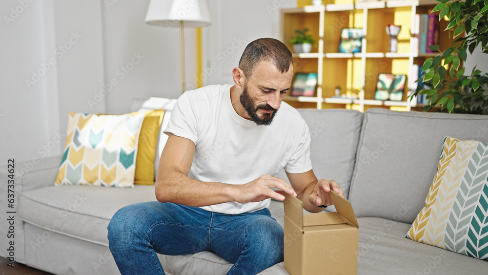 Young hispanic man unpacking cardboard box at home Young hispanic man unpacking cardboard box at home