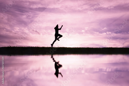 man jumping over a pond with a sunset  background © Ismael