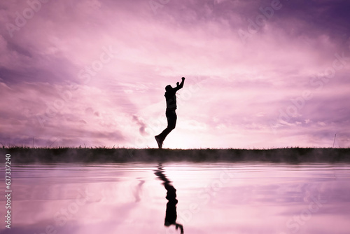 man jumping over a pond with a sunset background