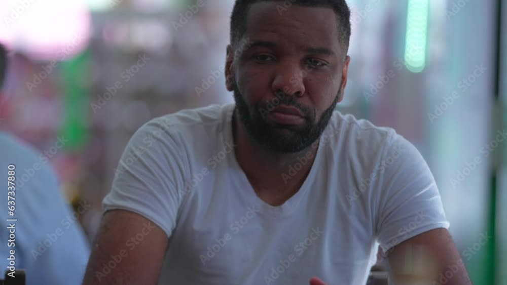 One pensive black man sitting and waiting at restaurant with thoughtful contemplative gaze One pensive black man sitting and waiting at restaurant with thoughtful contemplative gaze