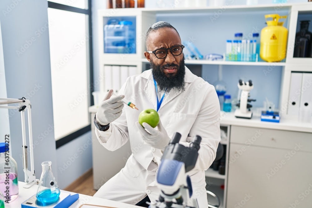 African american man working at scientist laboratory with apple clueless and confused expression. doubt concept. African american man working at scientist laboratory with apple clueless and confused expression. doubt concept.