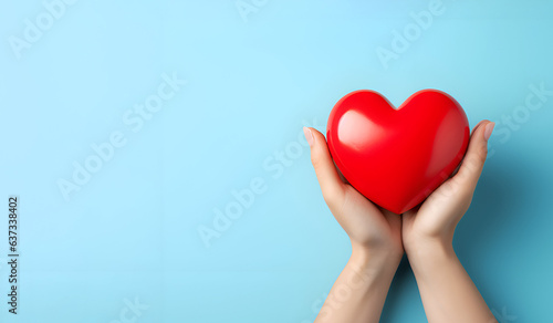 Fotografia Red heart in hands on a blue background 1