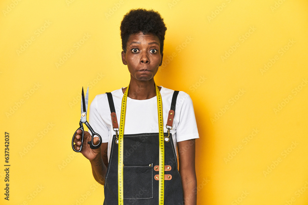 African tailor with scissors and measuring tape, fashion concept shrugs shoulders and open eyes confused. African tailor with scissors and measuring tape, fashion concept shrugs shoulders and open eyes confused.
