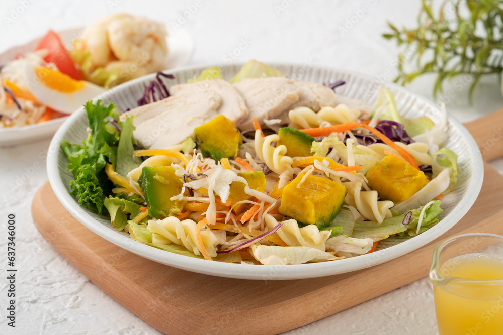 Fresh avocado lettuce salad bowl with chicken meat in a plate on white table background. Fresh avocado lettuce salad bowl with chicken meat in a plate on white table background.