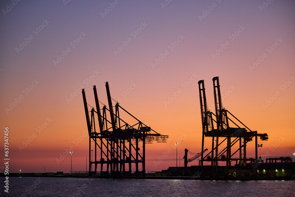 Harbor cargo cranes at sunset in Malaga port Spain