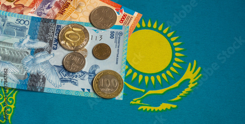 Kazakhstani tenge banknotes and coins with the national flag background photo