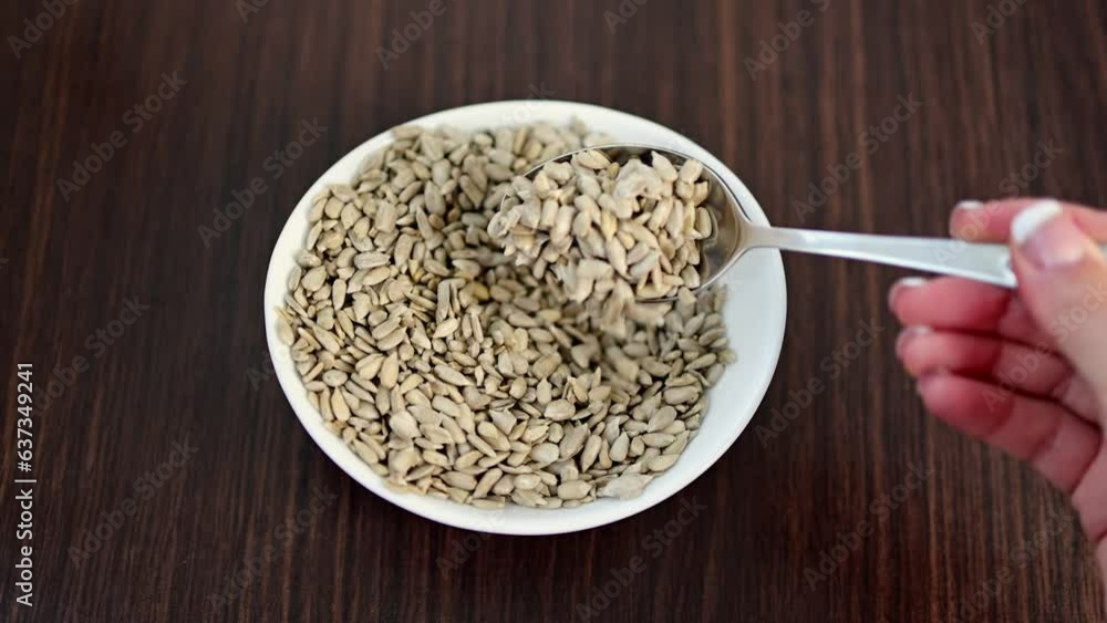 Sunflower kernels in a white bowl on a wooden table. Sunflower kernels in a white bowl on a wooden table.