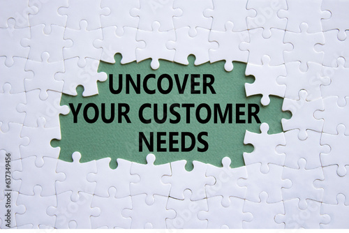 Customer Needs symbol. White puzzle with words Uncover your Customer Needs. Beautiful grey green background. Business concept. Copy space.