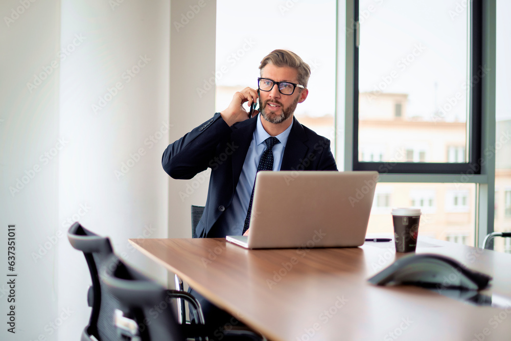 Businessman sitting in a modern office and using mobile phone and laptop for work Businessman sitting in a modern office and using mobile phone and laptop for work