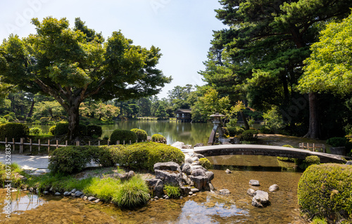 Panoramic view of a relaxing Japanese park with trees and a small bridge over water