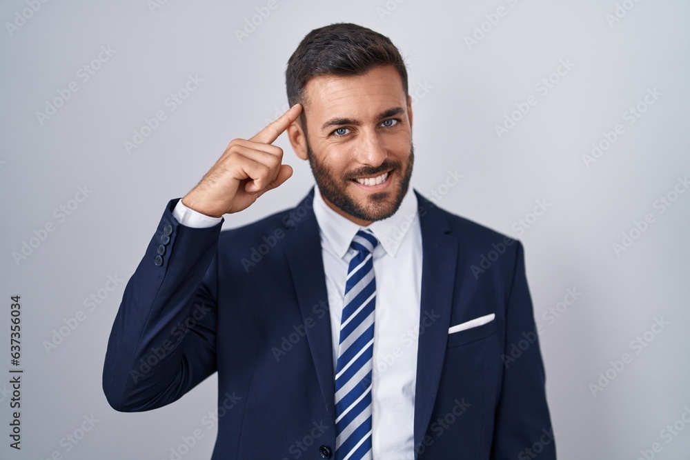 Handsome hispanic man wearing suit and tie smiling pointing to head with one finger, great idea or thought, good memory Handsome hispanic man wearing suit and tie smiling pointing to head with one finger, great idea or thought, good memory