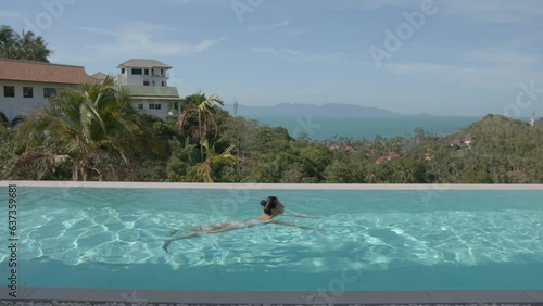 Woman swimming in private outdoors pool in sunny day, amazing view on tropical landscape and next villa, luxury vacation concept