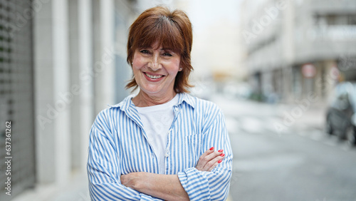 Middle age woman smiling confident standing with arms crossed gesture at street