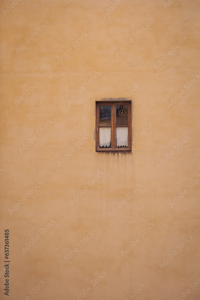Yellow Roman wall texture background, Italy. Old window on the shabby yellow wall facade. Little cute window on ochre colored stone wall. Old european house background. 
