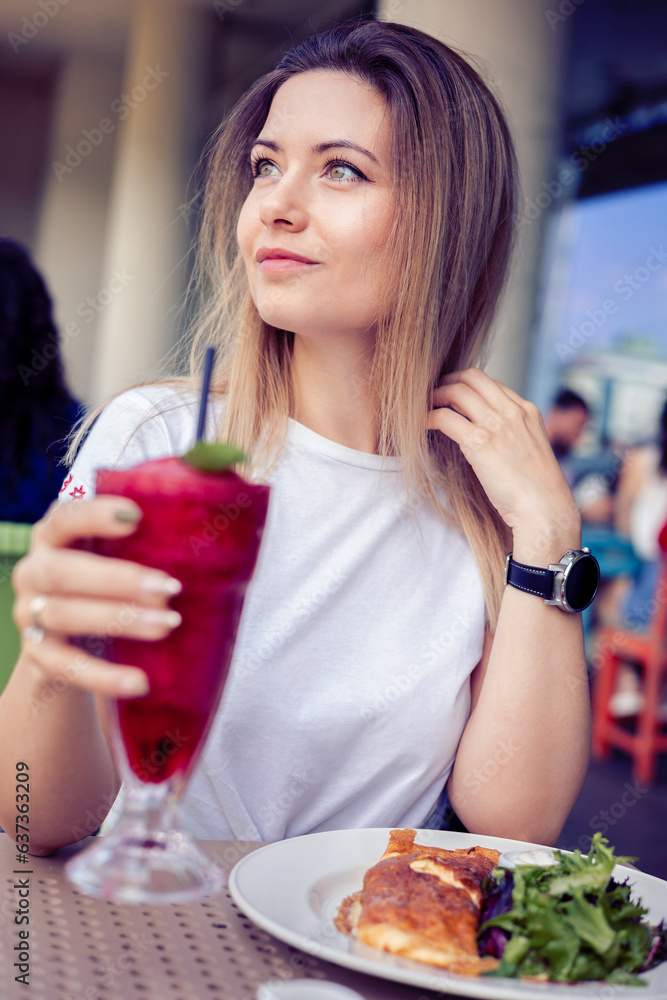 woman enjoying a vibrant red berry smoothie at a cafee