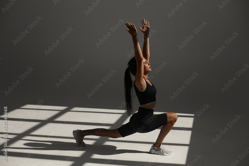 Φωτογραφία a tanned sports girl in a black suit is training in a yoga class in a fitness studio