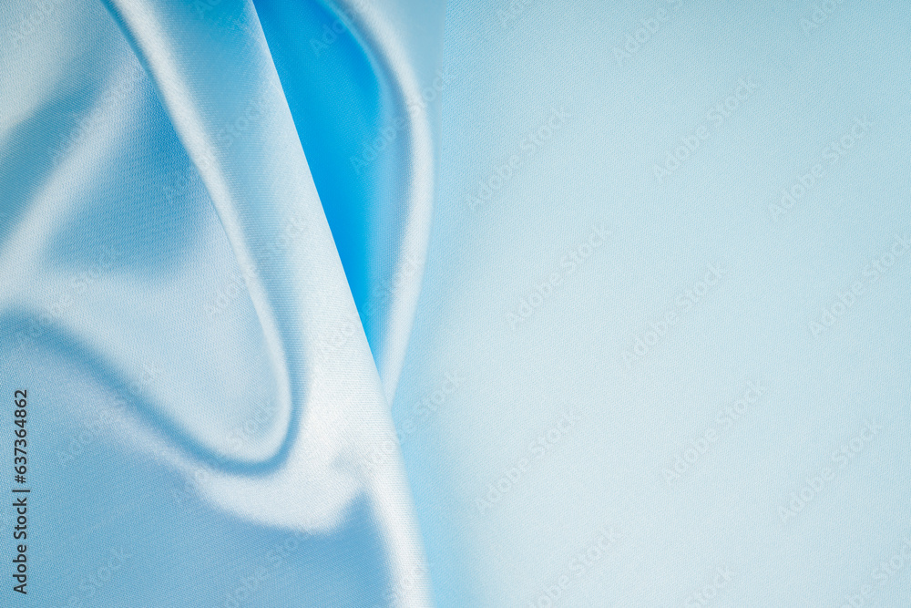Fototapeta premium The Soft wavy folds of light blue color silk satin background with copy space for your design.